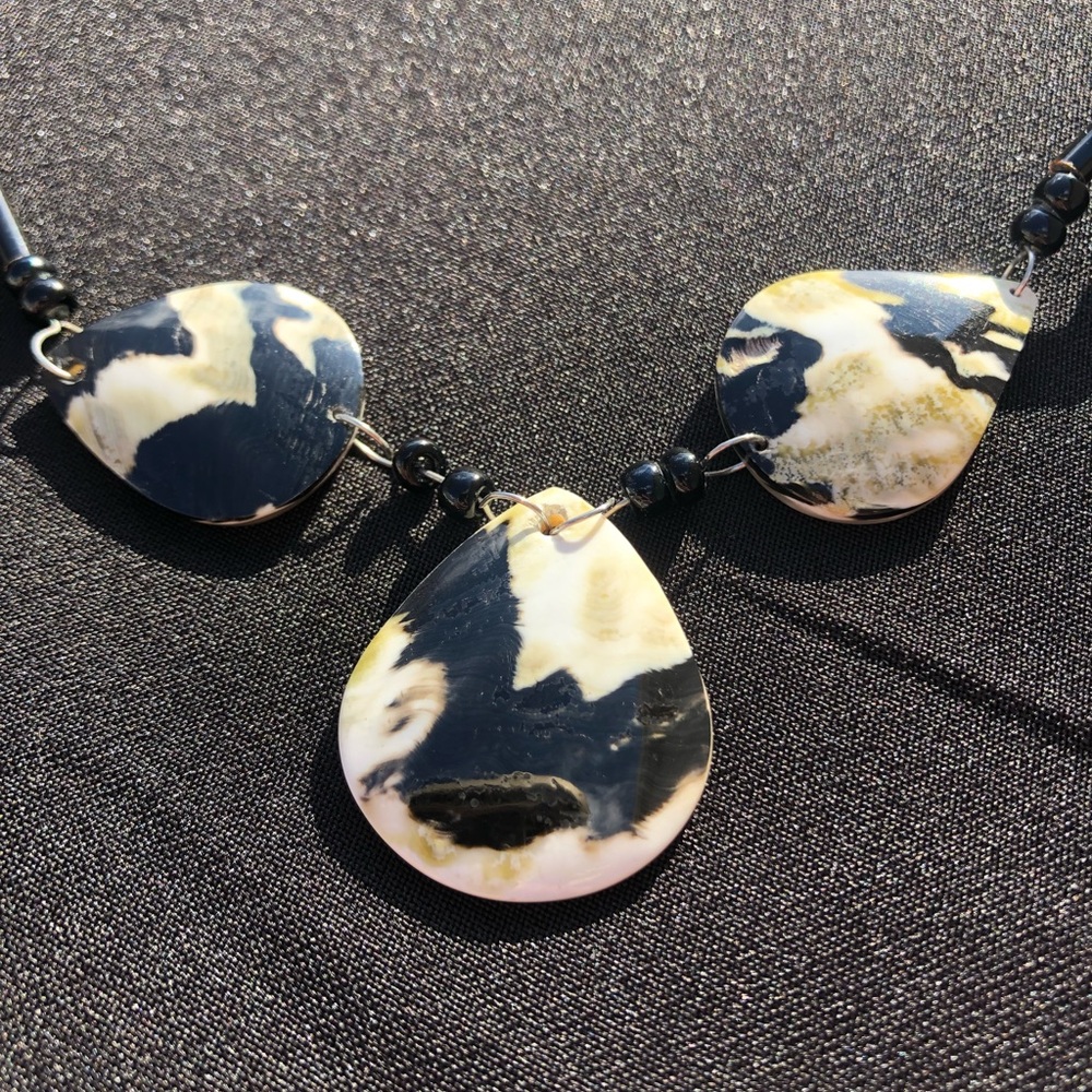 Black bead necklace with three teardrop design on mother of pearl